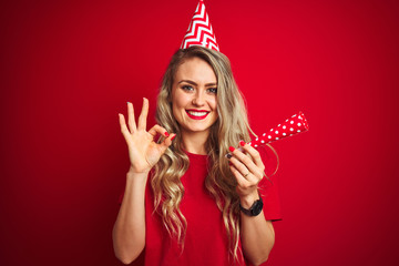 Young beautiful woman on birthday celebration over red isolated background doing ok sign with fingers, excellent symbol