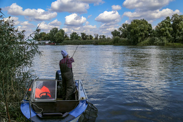 Fisherman with spinning reel on the river bank. Sunrise. Fishing for pike, perch, carp.   wild nature. The concept of a rural getaway.