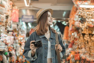 Smiling woman traveler in chiangmai market landmark chiangmai thailand holding camera with backpack on holiday, relaxation concept, travel concept