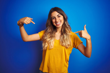 Young beautiful woman wearing yellow t-shirt over blue isolated background looking confident with...