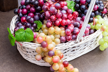 Bunches of artificial grapes in a wicker basket