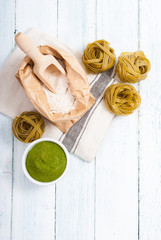 uncooked taglatelle pasta and ingredients: grounded spinach powder and whole wheat flour
