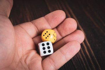 dice in hand on a wooden background, two dice and on both the number six, a jackpot of sixes,...