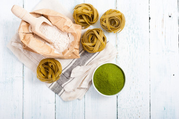 uncooked taglatelle pasta and ingredients: grounded spinach powder and whole wheat flour