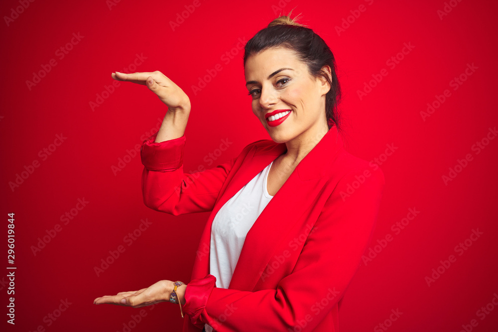 Wall mural young beautiful business woman standing over red isolated background gesturing with hands showing bi