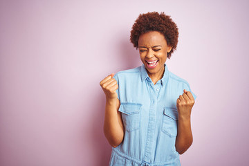 Young beautiful african american woman with afro hair over isolated pink background very happy and excited doing winner gesture with arms raised, smiling and screaming for success