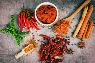 peppercorns curry paste cayenne pepper on wooden spoon herbs and spices star anise cinnamon dried...