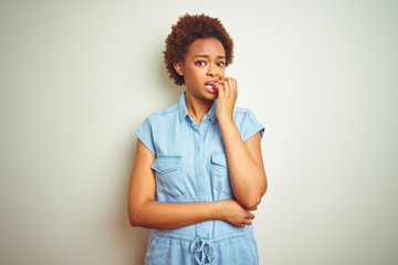 Young beautiful african american woman with afro hair over isolated background looking stressed and nervous with hands on mouth biting nails. Anxiety problem.