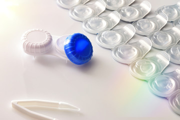 Contact lenses blister and case on white table elevated detail