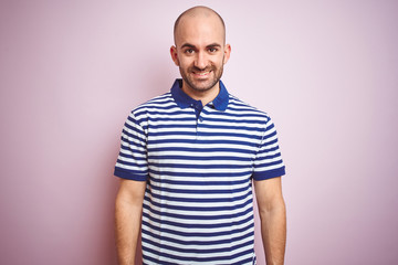 Young bald man with beard wearing casual striped blue t-shirt over pink isolated background with a happy and cool smile on face. Lucky person.