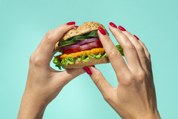Person holding a fresh tasty burger