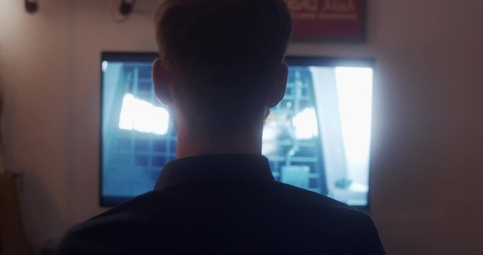 Man with short hair and a beard looking at a TV and watching netflix/a film.