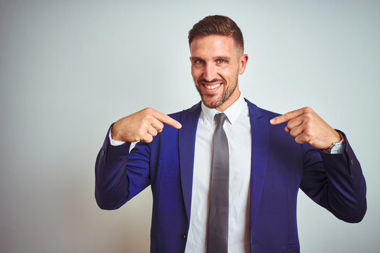 Young handsome business man over white isolated background looking confident with smile on face, pointing oneself with fingers proud and happy.