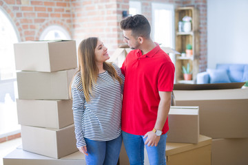 Fototapeta na wymiar Young beautiful couple in love around cardboard boxes moving to new home, smiling very happy and cheerful for new apartment