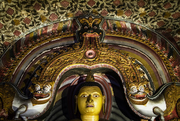 The head of the Buddha statue is framed by traditional Sri Lankan patterns of the first millennium AD, with snow lions on the side, and the head of a mystical animal on top. Temple Cave Complex in Dam