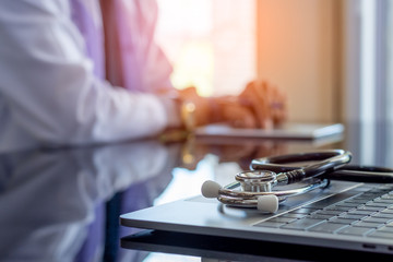 Male doctor use tablet computer, work on laptop computer at office.