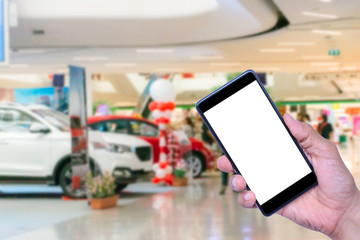 Mock up image of woman hand holding mobile smartphone with blank white screen on motor car show room