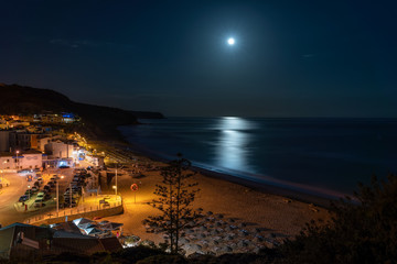 Night beach of the village of Salema, with the moon over the sea. Portugal.