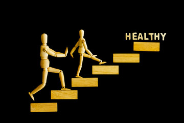 Ascending step stairs and wooden man model going upward to healthy word isolated on wooden background. Encourage and inspiration to take care yourself for healthy. 