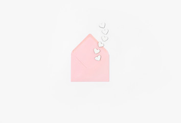 Open envelope with letter and wooden hearts on white background
