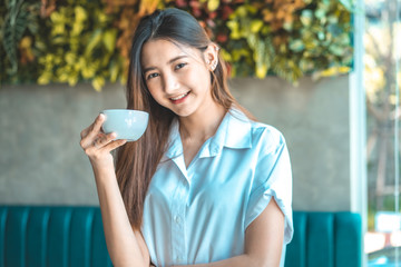 Asian woman in a cafe drinking coffee .Portrait of Asian woman smiling in coffee shop cafe vintage colour tone.
