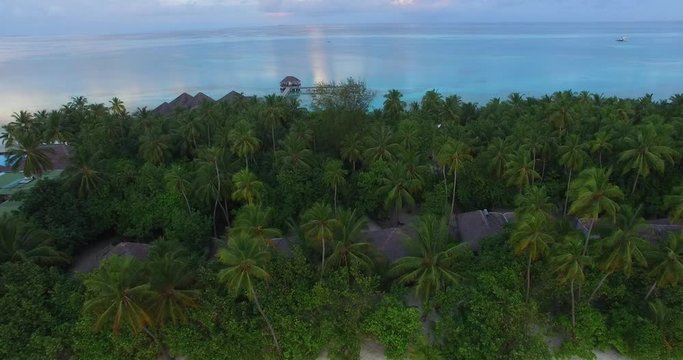 4K Aerial drone view of a luxury island resort on exotic white sand beach and over-water villas in Maldives. Blue lagoon and palm trees. Travel agency and trip advisor concept