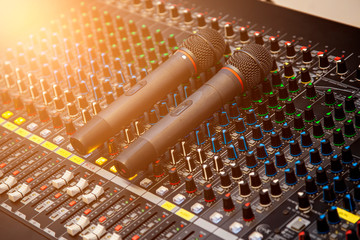 Microphone placed on the sound mixer with orange flare at the audio control room. - obrazy, fototapety, plakaty