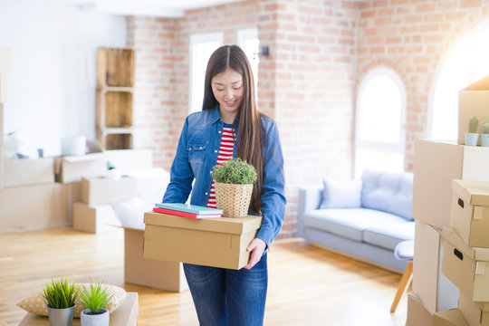 Beautiful asian young woman holding boxes, smiling happy moving to a new home