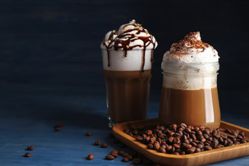 Glasses of tasty frappe coffee with beans on table