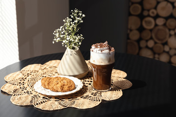 Glass of tasty frappe coffee with cookies on table in cafe