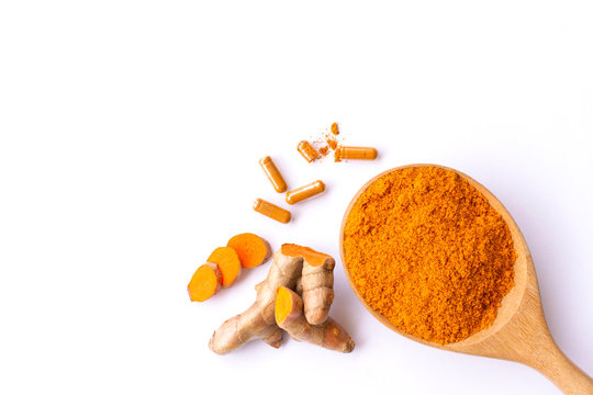 Turmeric powder in wooden spoon with curcuma ground root and tumeric capsules isolated on white background. Natural medicine plant,alternative medical healthcare and supplement concept.Top view.(flat)