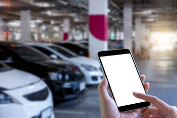 Mockup woman hands holding and using blank screen mobile smart phone with car parking blurred background. Clipping path. 