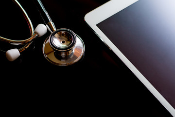 Mockup medical stethoscope and white tablet computer pc. with empty screen isolated on dark background. Medic tech, online medical and technology  concept. Top view.