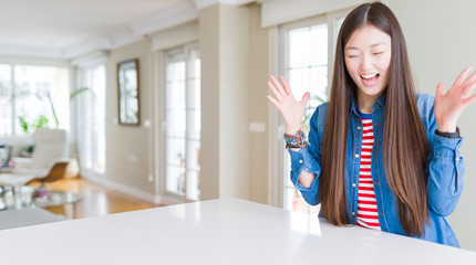 Young beautiful asian woman with long hair wearing denim jacket celebrating mad and crazy for success with arms raised and closed eyes screaming excited. Winner concept
