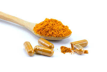 Turmeric powder in wooden spoon and tumeric capsules isolated on white background. 