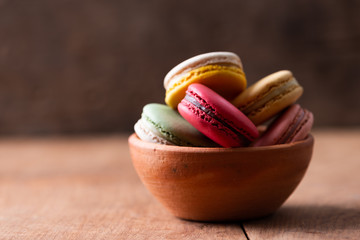 Pile of sweet and colourful french macaroons on wood background.