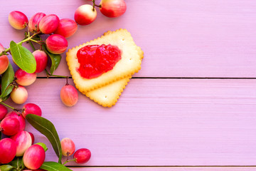 Bengal currants or Carissa carandas Linn , Karanda ,Carunda ,Karonda , ,Koromcha fruits with cookie and jam isolated on pink wooden board background. Top view. 
