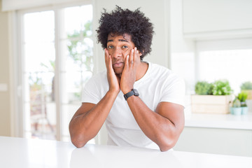 Young african american man wearing casual white t-shirt sitting at home Tired hands covering face, depression and sadness, upset and irritated for problem