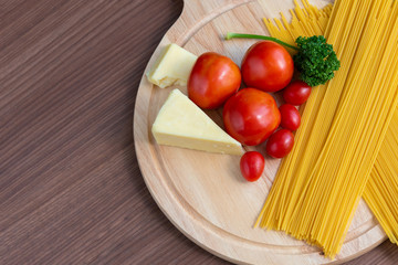 Spaghetti, tomatoes, broccoli and butter on a brown wooden floor