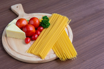 Spaghetti, tomatoes, broccoli and butter on a brown wooden floor