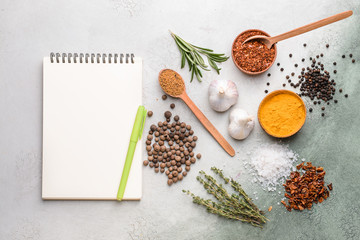 Empty notebook with different spices on light background