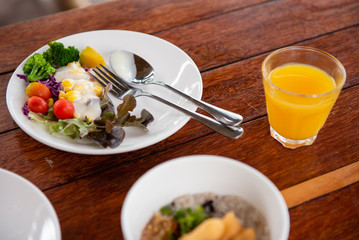 vegetable salads, sausages, fried rice, milk and orange juice on a brown wooden table