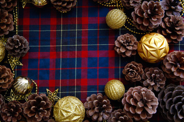 Frame of christmas decorations cones and golden balls on the blue-red plaid background. New Year Flat lays concept. 