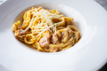 Delicious spaghetti, bacon topped with cheese, served on a white plate