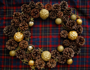 Frame of christmas decorations cones and golden balls on the blue-red plaid background. New Year Flat lays concept. 