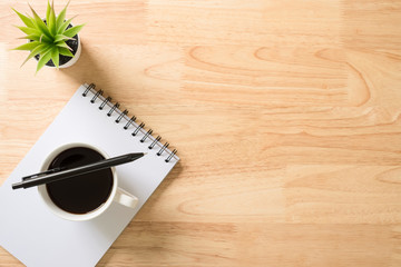 Flat lay, top view office table white desk. Workspace with notepad, pen, green leaf, and coffee cup on white background.