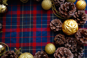 Frame of christmas decorations cones and golden balls on the blue-red plaid background. New Year Flat lays concept. 
