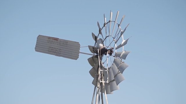 Old Farm Windmill spinning in the wind with blue sky background 