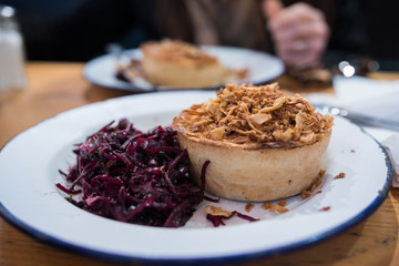 Chicken homemade gluten free pot pie from award-winning Pieminister (Oxford, Covered Market, United Kingdom). Delicious meal with crispy onions for topping and fresh coleslaw. Close up picture.