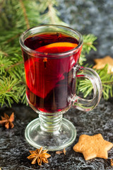 Christmas mulled wine with ginger biscuits orange cinnamon clove anise and fir tree on the dark table